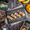 Dessert with coconut milk on a dark slate board surrounded by ingredients and packaging on a wooden surface.