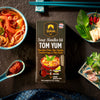 Siam Tom Yum soup noodles kit packaging with ingredients on a dark surface